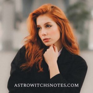 A redheaded young woman wears a black coat ans poses casually in front of the photographer. There is a written text on the image, says: astrowitchsnotes.com