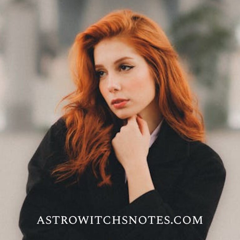 A redheaded young woman wears a black coat ans poses casually in front of the photographer. There is a written text on the image, says: astrowitchsnotes.com